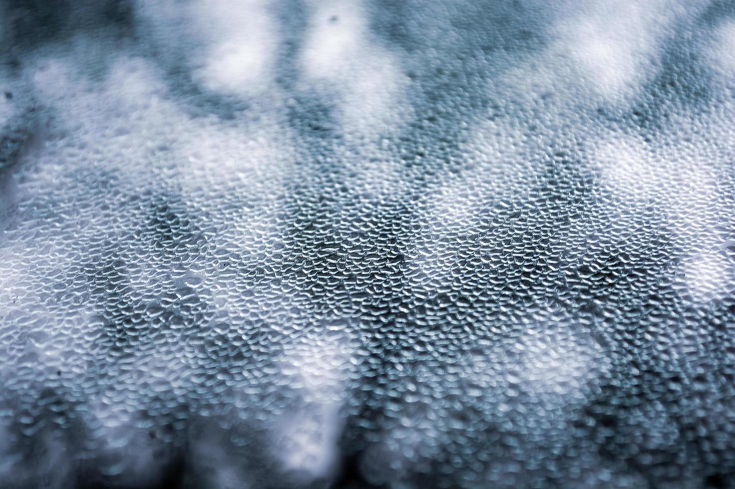 derritiendo pequeños trozos de hielo en el cristal de la ventana en forma de escamas. fondo abstracto. foto