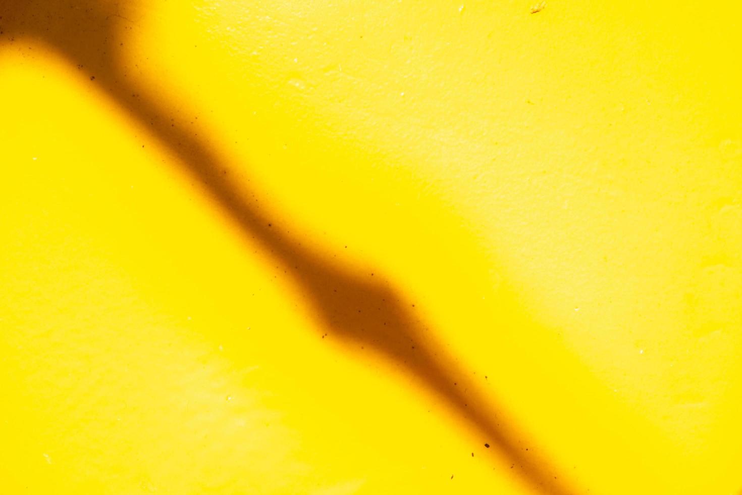 A diagonal thin shadow on the old faded yellow paint which is covered with metal. Abstract background. photo