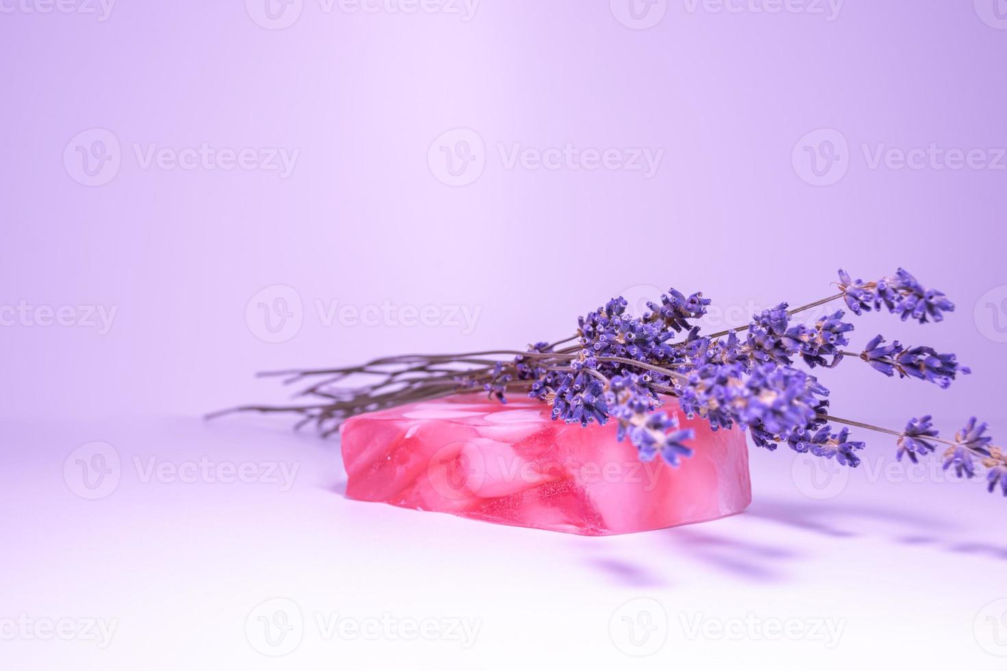 Jabón artesanal con aroma a flores de lavanda sobre un delicado fondo lila. foto