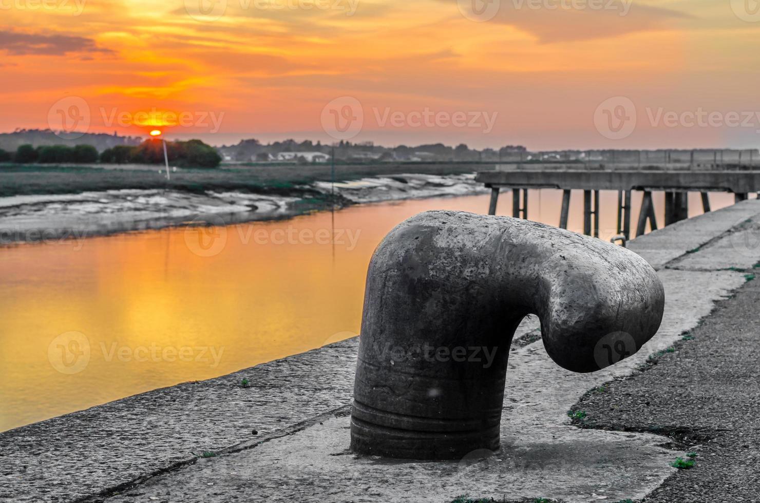 Bolardo de amarre, cornamusa de hierro con colorido atardecer foto