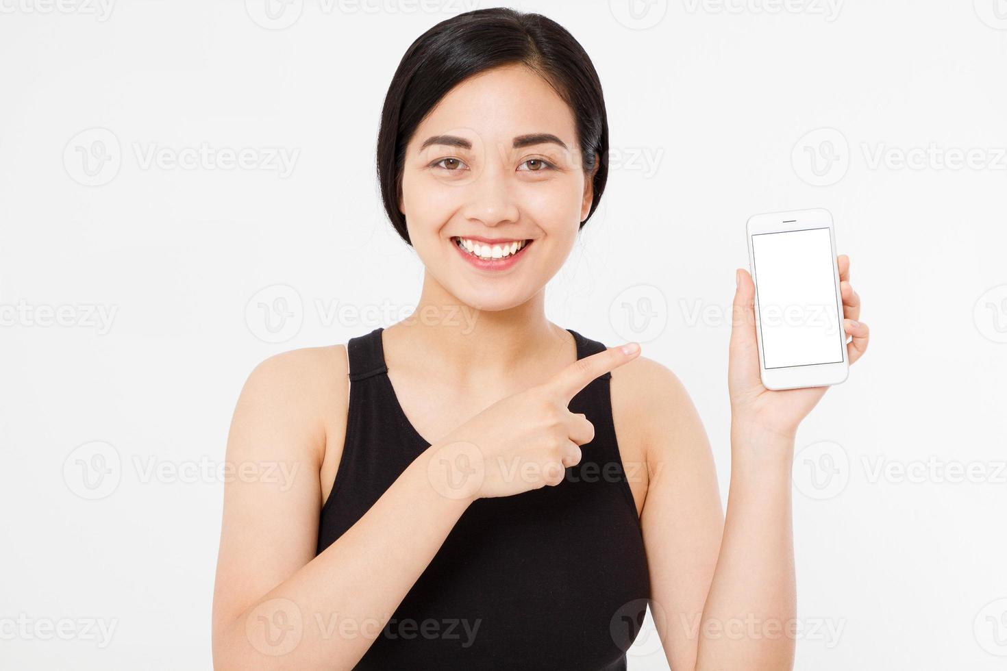 Sonriente mujer japonesa asiática mantenga blanco smartphone o teléfono móvil aislado sobre fondo blanco textura concepto publicitario. expresión facial positiva emoción humana. copie el espacio. foto