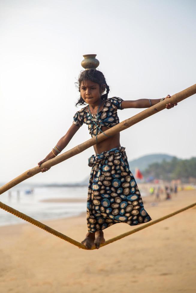 anjuna, india, 14 de octubre de 2015 - niña de goa no identificada en la cuerda floja en la playa de anjuna. foto