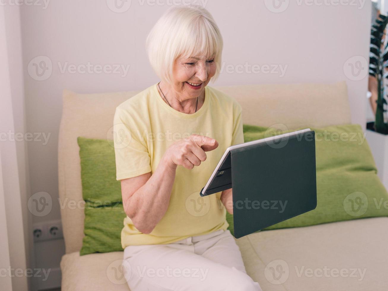 senior cheerful caucasian stylish woman with gray hair with her tablet at home. Technology, emotions, family, healthy lifestyle, positive thinking concept photo