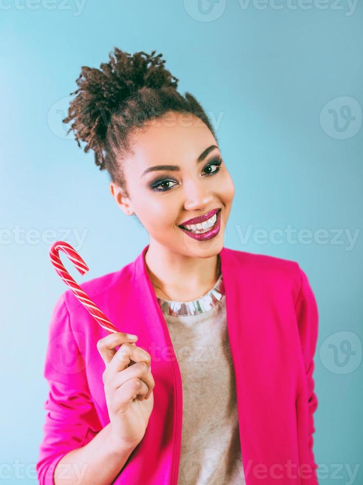 mujer afroamericana alegre y feliz con bastón de caramelo. navidad, año nuevo, azúcar, felicidad, concepto de vacaciones foto