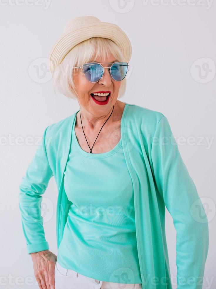 senior stylish cheerful woman in blue sunglasses and turquoise clothes. Summer, travel, anti age, joy, retirement, freedom concept photo