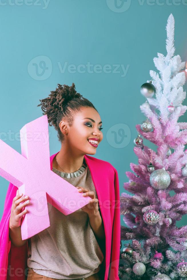 Happy and cheerful afro american woman with present box on the christmas tree background. Christmas, new year, happiness, holidays concept photo