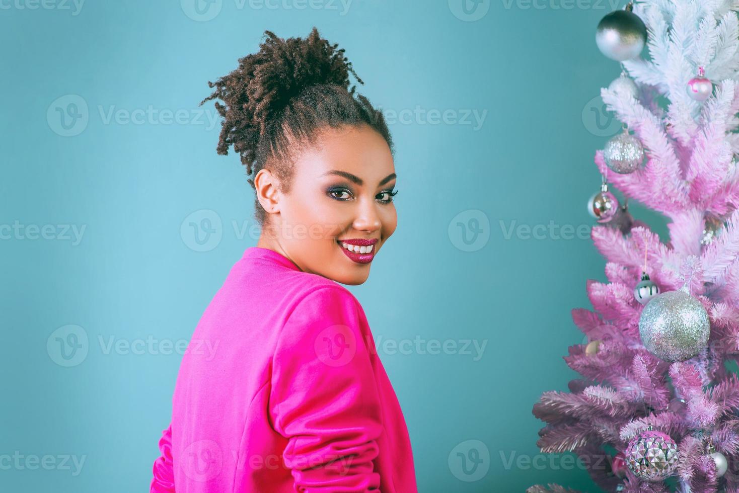 Feliz y alegre mujer afroamericana con cuadro actual en el fondo del árbol de Navidad. navidad, año nuevo, felicidad, concepto de vacaciones foto