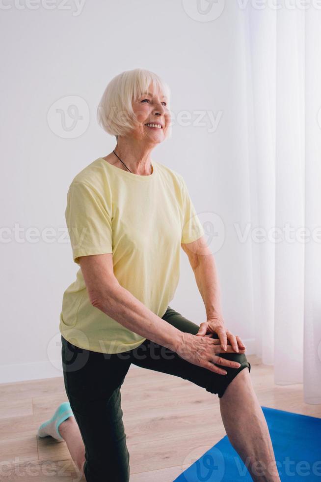 senior woman doing yoga online indoor. Anti age, sport, technology, yoga concept photo