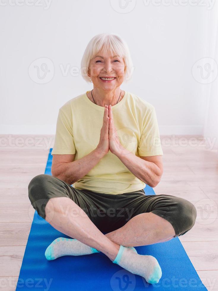 senior woman doing yoga online indoor. Anti age, sport, technology, yoga concept photo