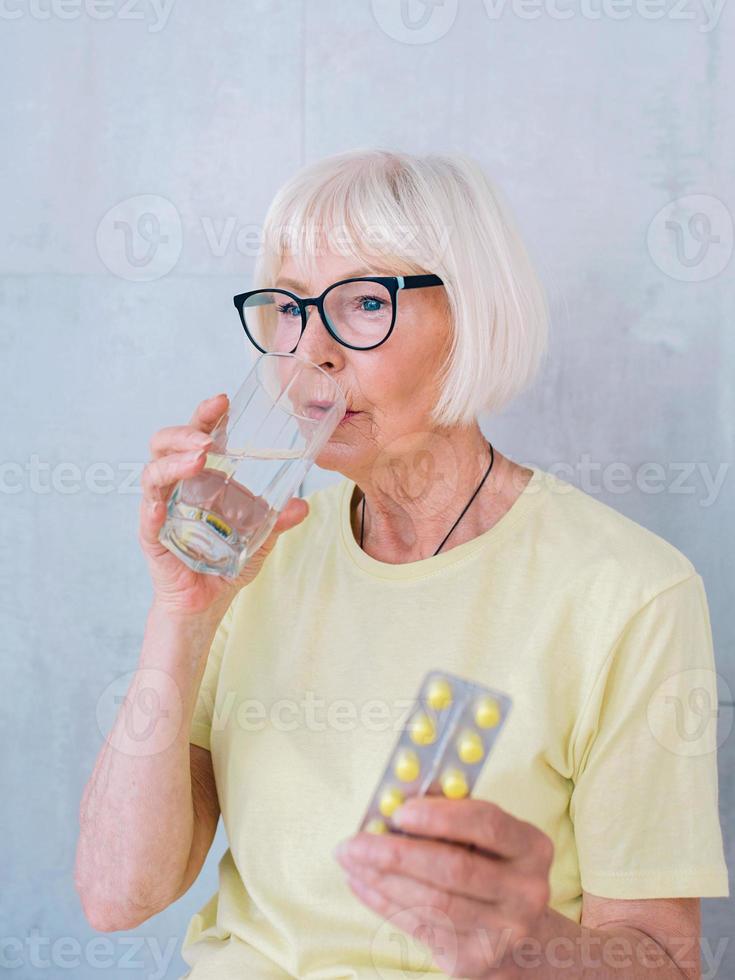 mujer mayor en vasos con medicina y vaso de agua. edad, cuidado de la salud, concepto de tratamiento foto