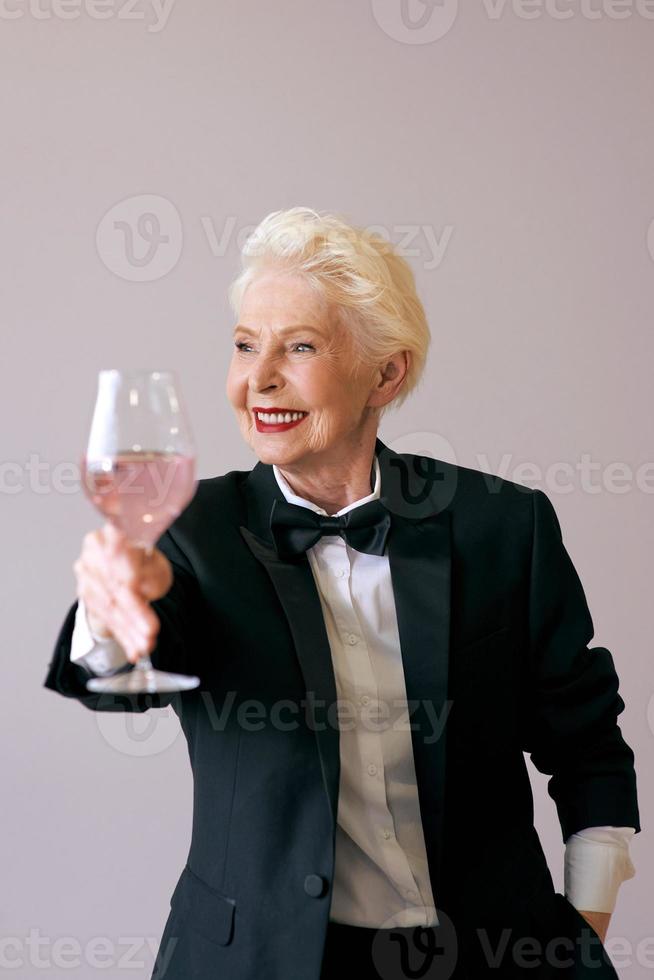 stylish mature sommelier senior woman in tuxedo with glass of wine. Fun, party, style, lifestyle, work, alcohol, celebration concept photo