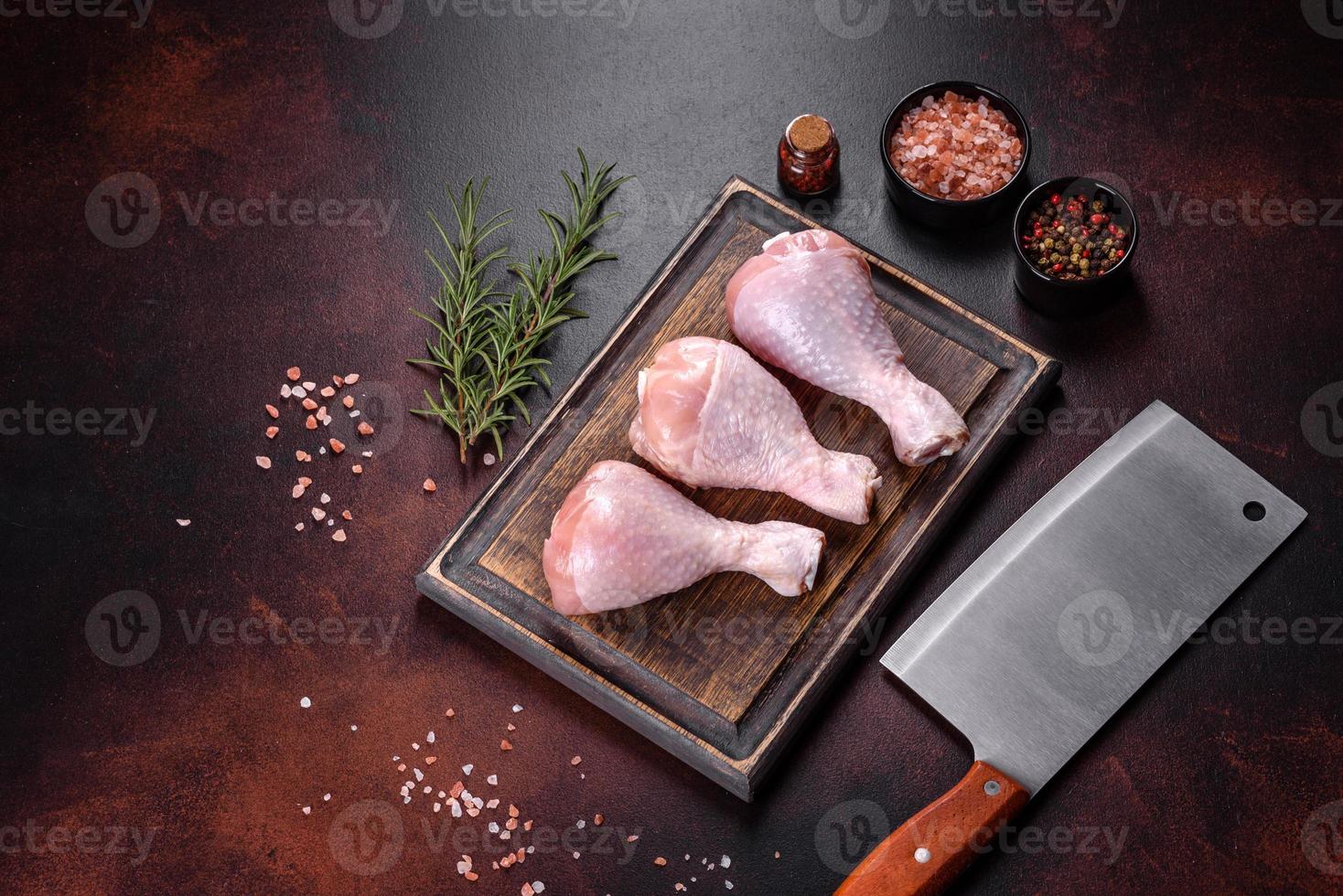 Muslos de pollo crudo fresco con especias, sal y hierbas sobre una tabla para cortar foto