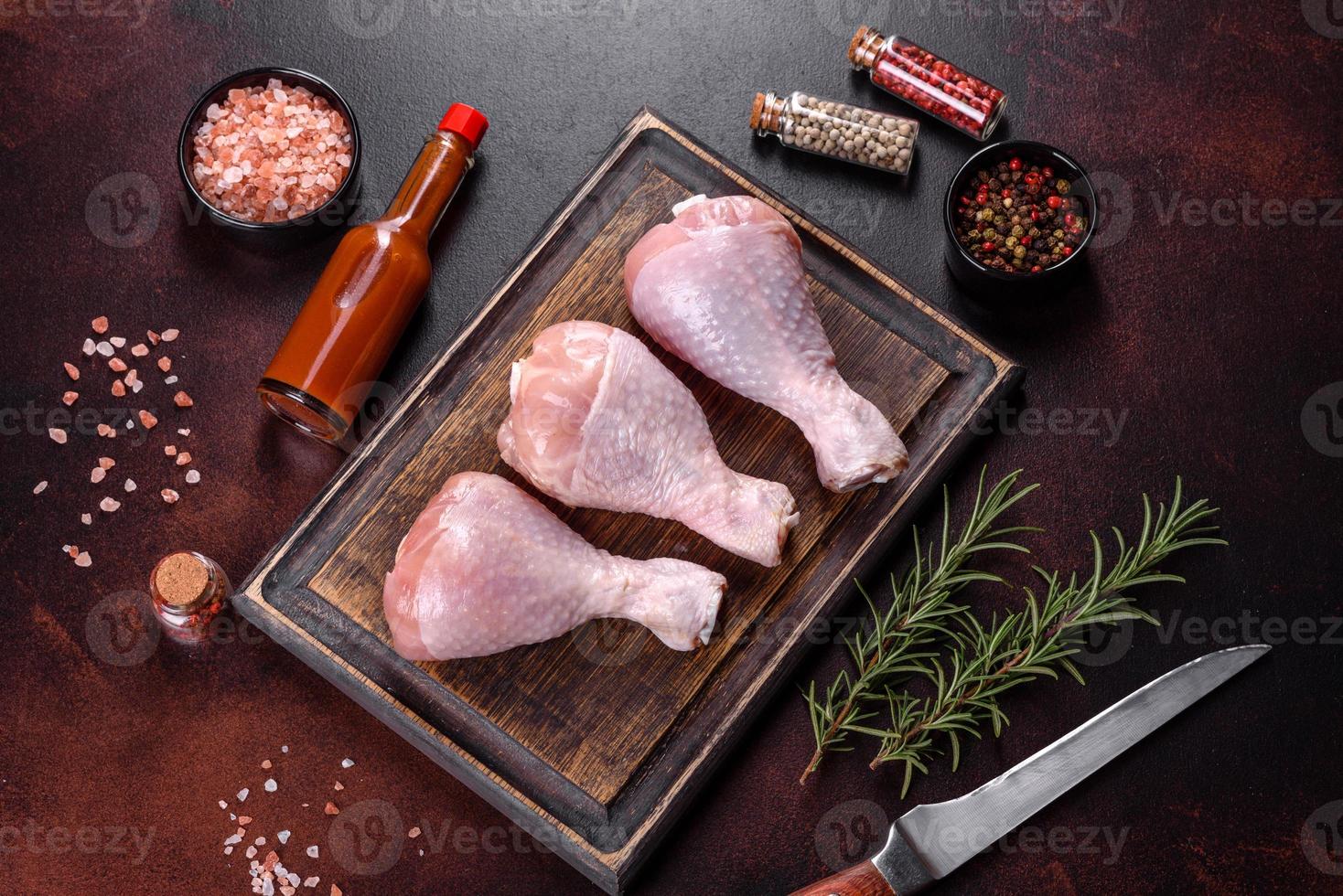 Fresh raw chicken legs with spices, salt and herbs on a cutting board photo
