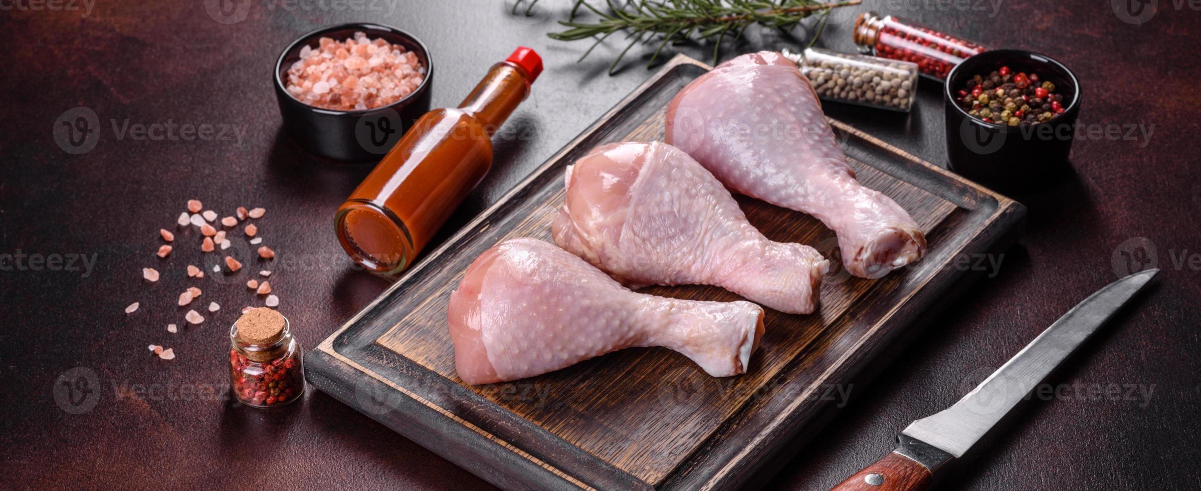 Fresh raw chicken legs with spices, salt and herbs on a cutting board photo