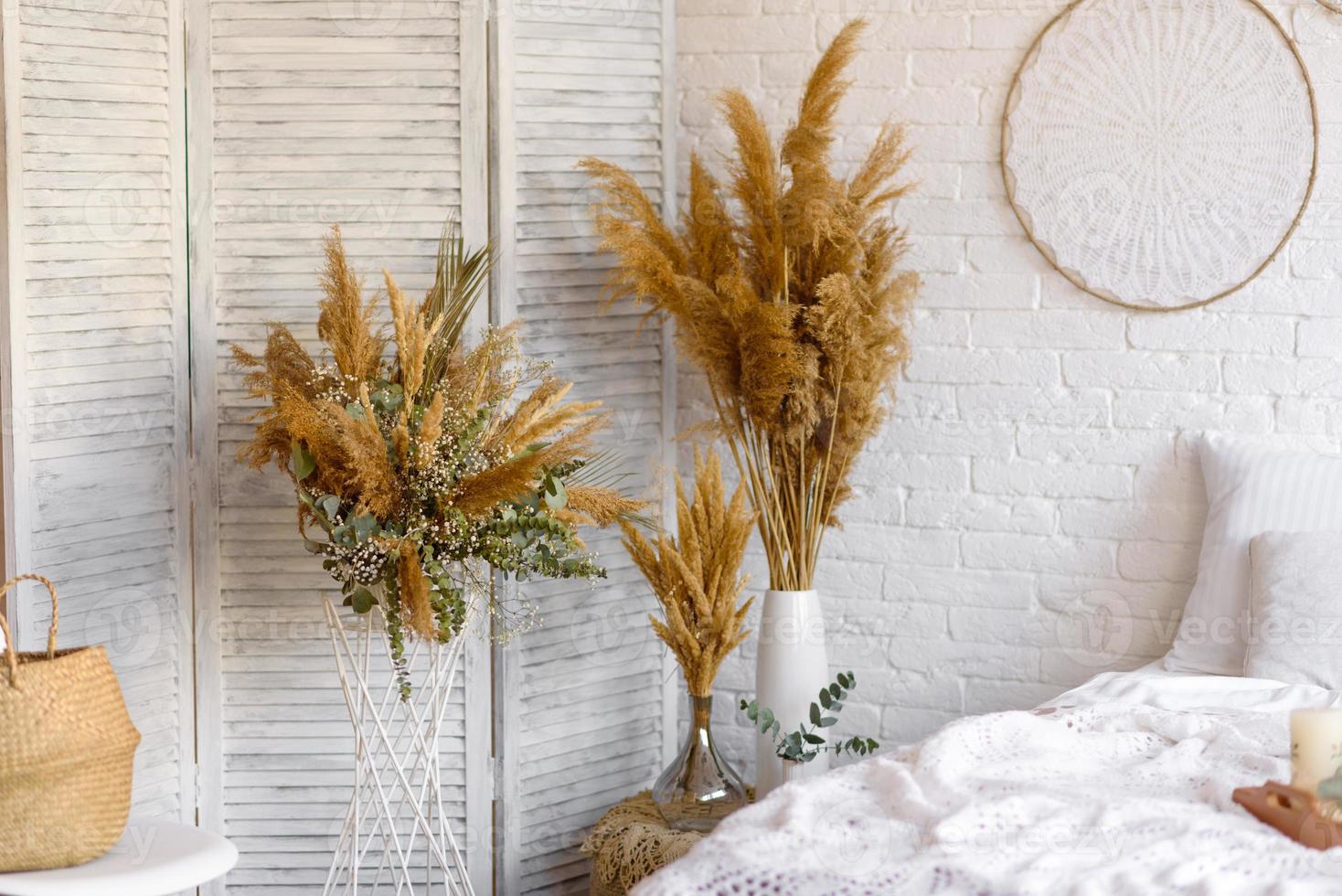 Beautiful home interior with white and beige tones, with dream catchers, dry flowers and a bed photo