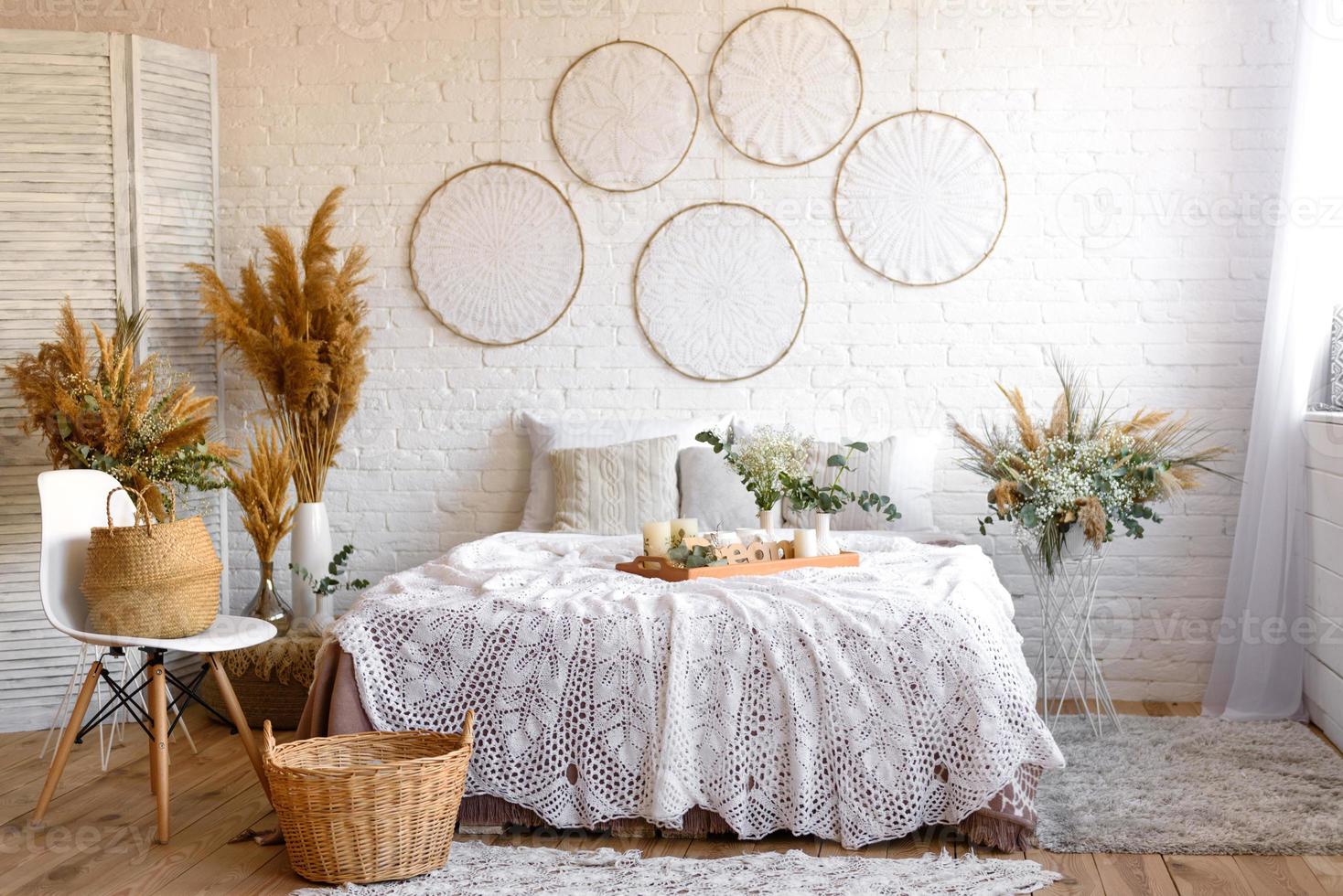 Beautiful home interior with white and beige tones, with dream catchers, dry flowers and a bed photo