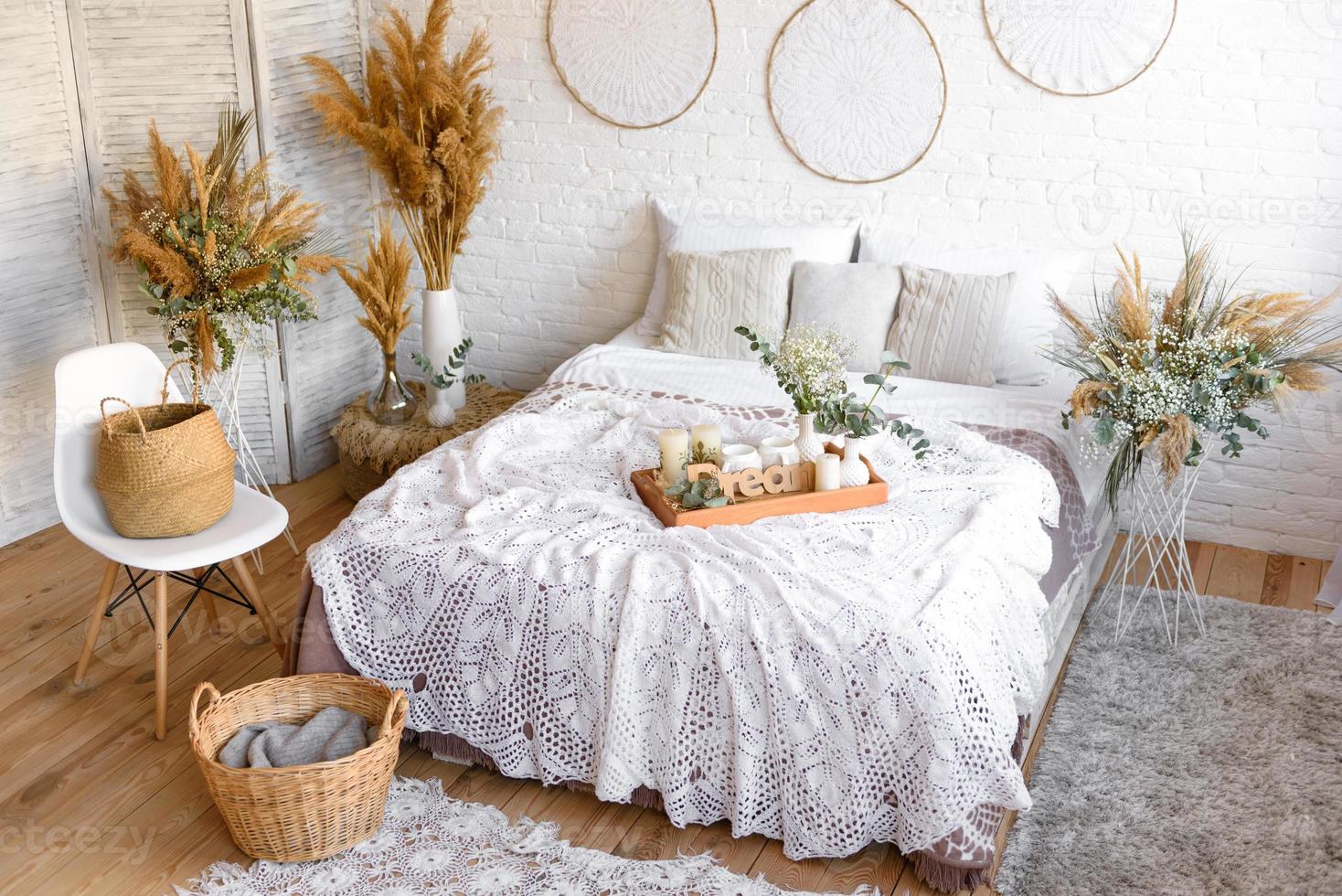 Beautiful home interior with white and beige tones, with dream catchers, dry flowers and a bed photo