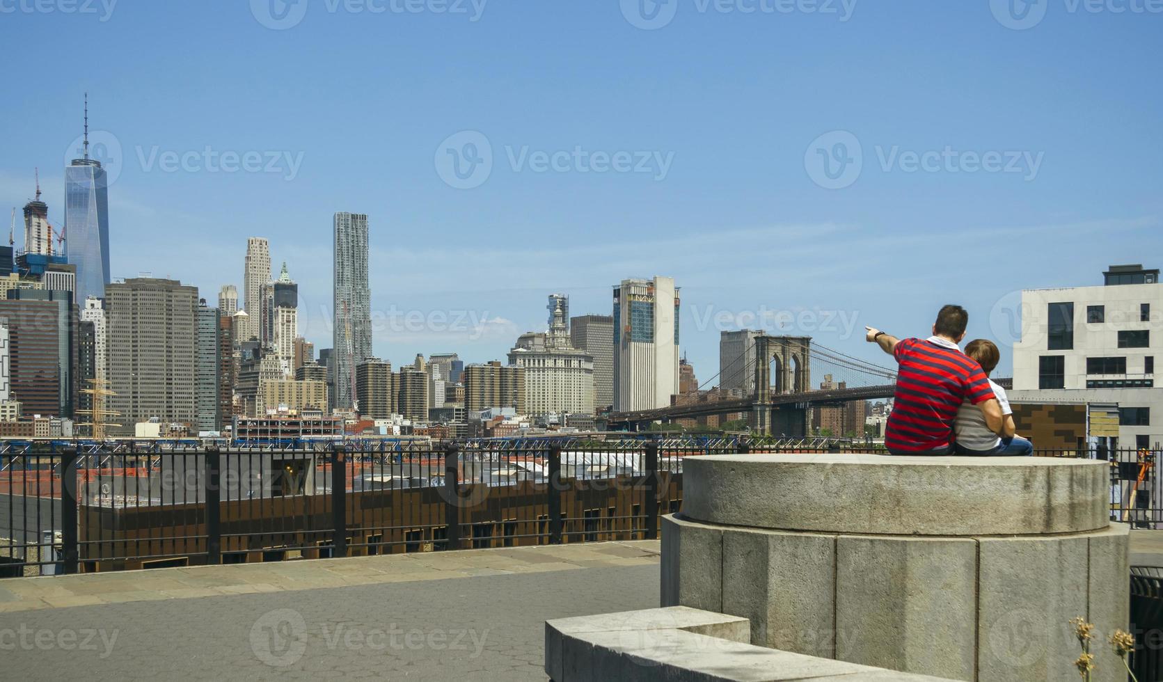 Man showing to kid the Manhattan skyline in New York City photo