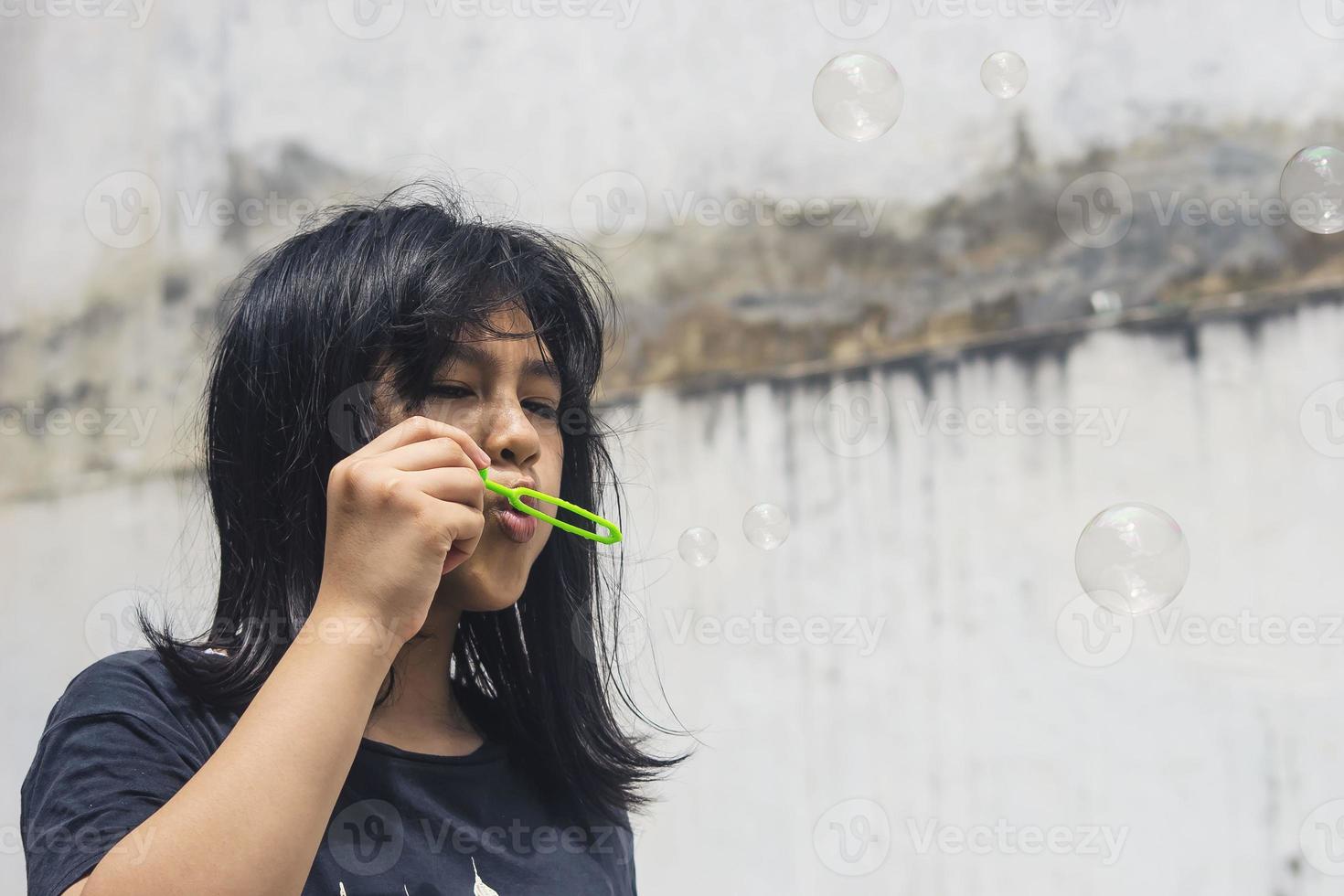 A girl holding a bubble maker and blowing them out. photo