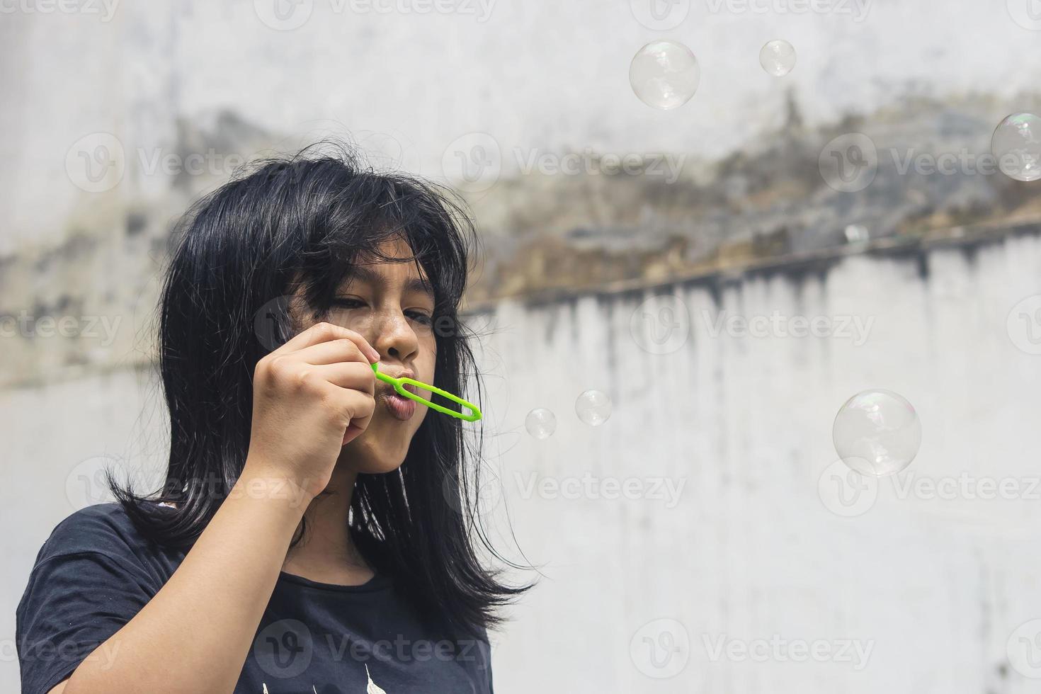 una niña que sostiene una máquina de hacer burbujas y las sopla. foto