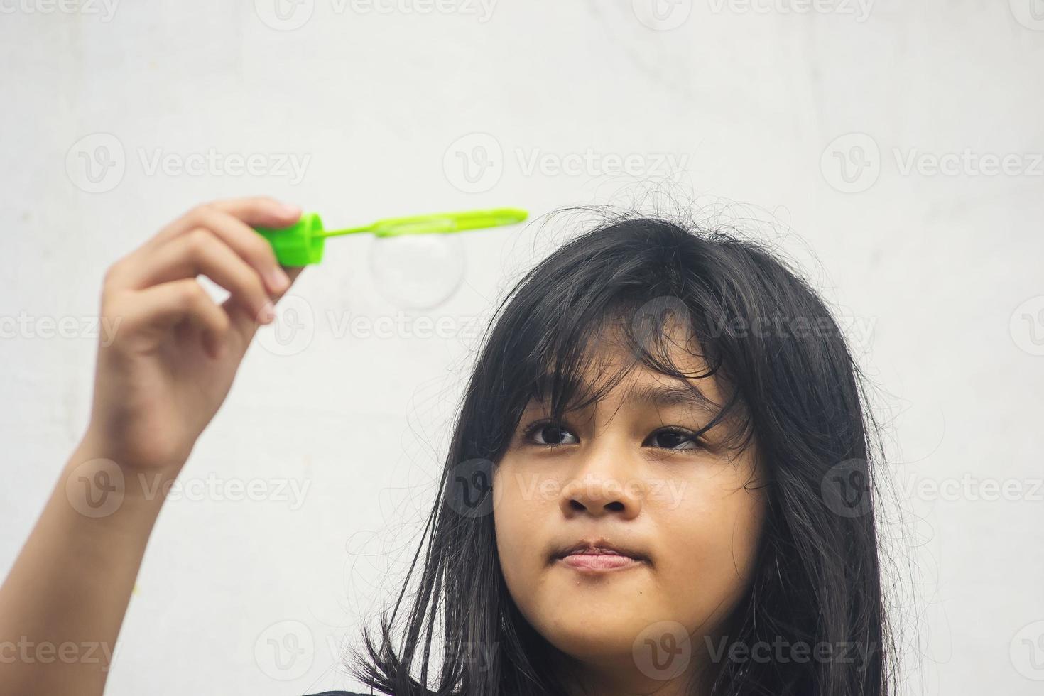 una niña que sostiene una máquina de hacer burbujas y las sopla. foto