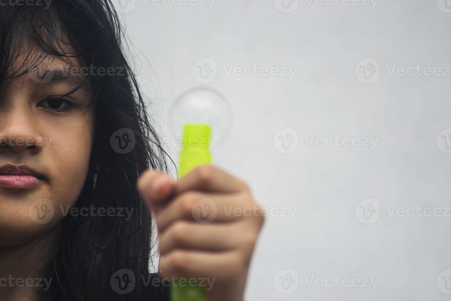 una niña que sostiene una máquina de hacer burbujas y las sopla. foto