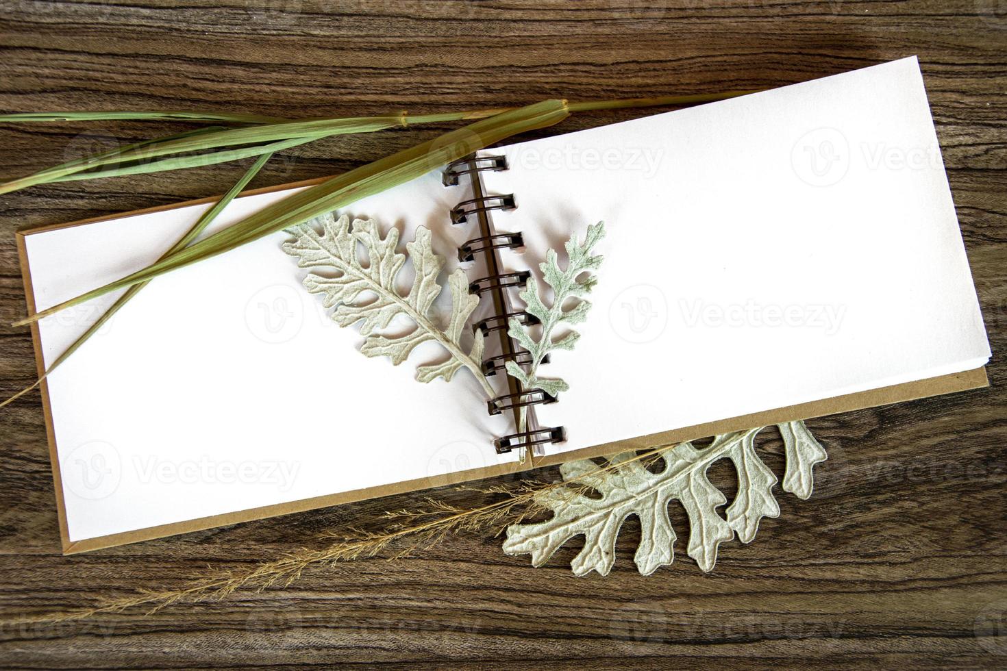 Notepad and dry autumn leaves. Readable white sheet for text. Card. photo