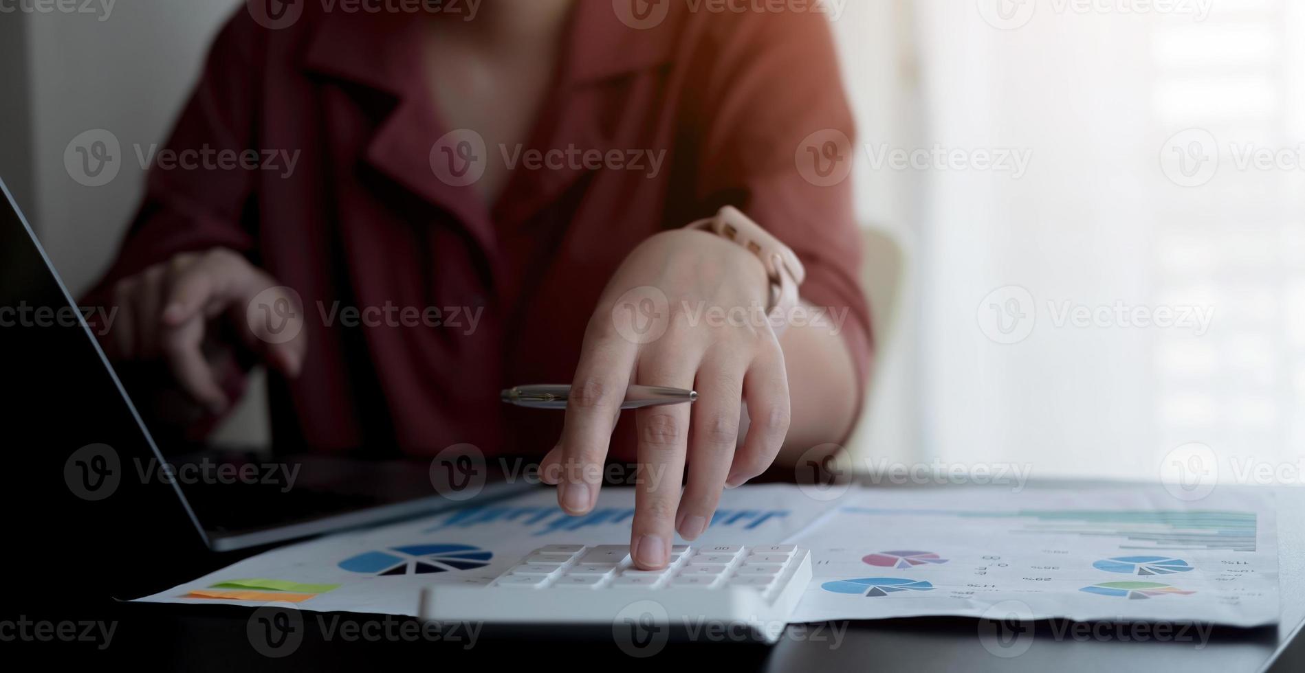 Close up Business woman using calculator and laptop for do math finance on wooden desk in office and business working background, tax, accounting, statistics and analytic research concept photo