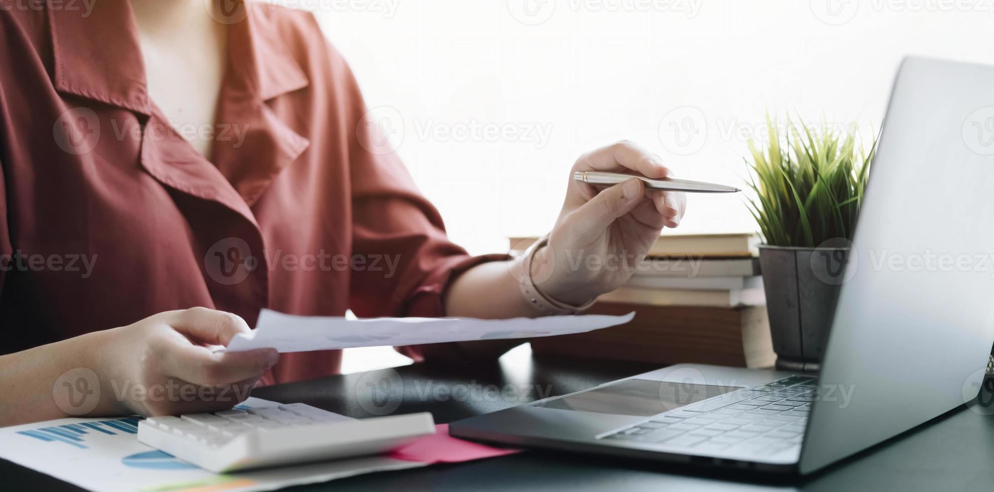 Close up Businessman hand holding pen and pointing at financial paperwork, financial charts to analyze profit concept photo