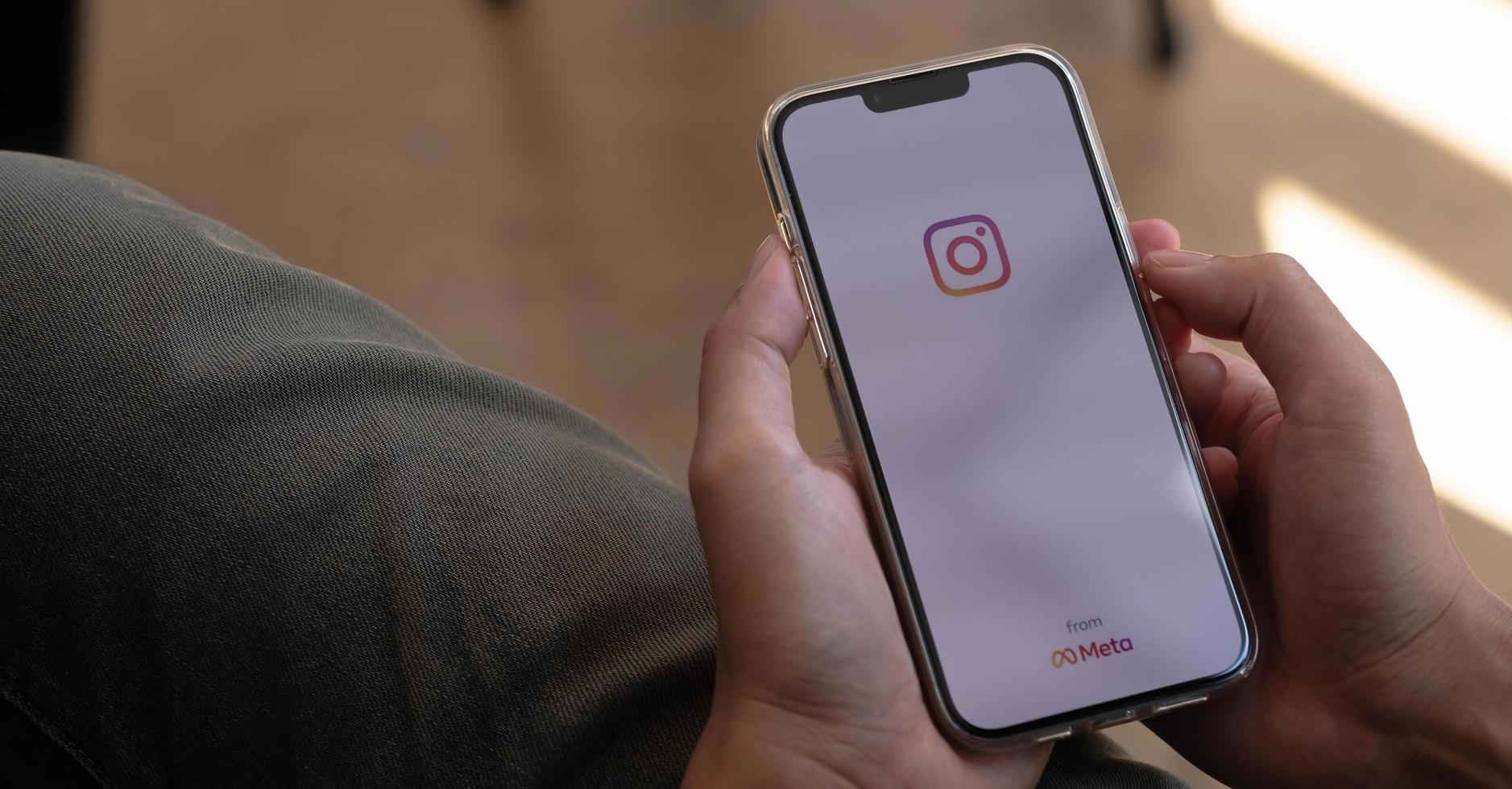 A man holds Apple iPhone 13 Pro with Instagram application on the screen at cafe. Instagram is a photo-sharing app for smartphones. photo