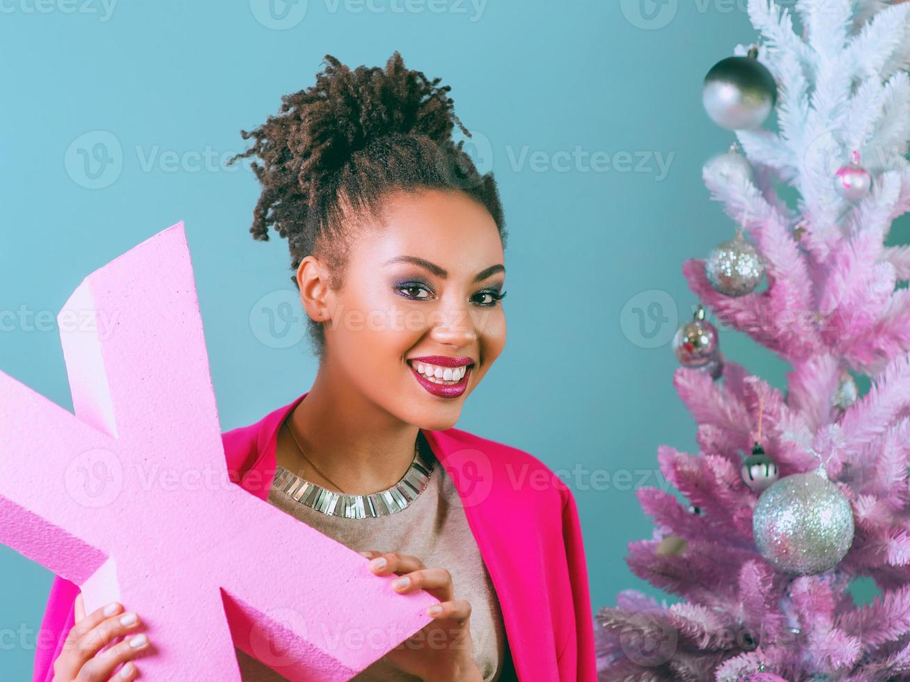 Feliz y alegre mujer afroamericana con cuadro actual en el fondo del árbol de Navidad. navidad, año nuevo, felicidad, concepto de vacaciones foto