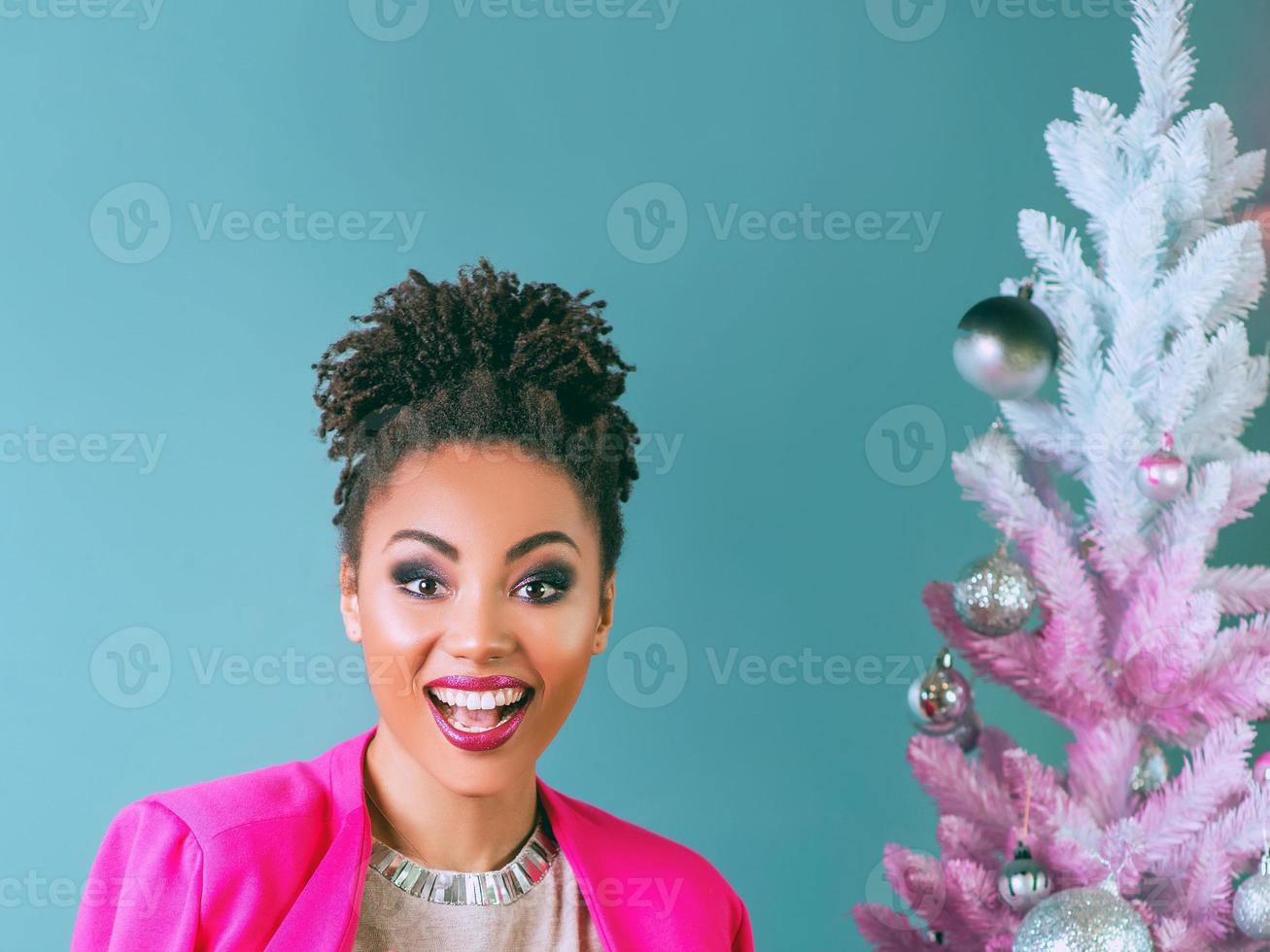 Happy and cheerful afro american woman with present box on the christmas tree background. Christmas, new year, happiness, holidays concept photo