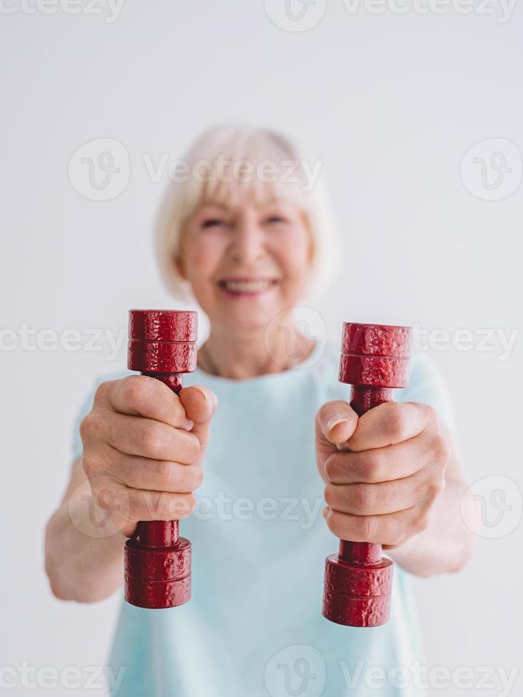 senior cheerful woman doing sports with dumbbells. Anti age, sports, healthy life style concept photo