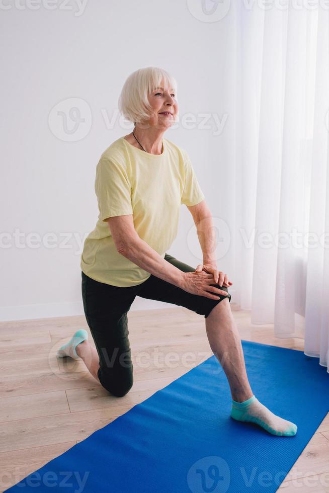 mujer mayor haciendo yoga en línea en interiores. anti edad, deporte, tecnología, concepto de yoga foto