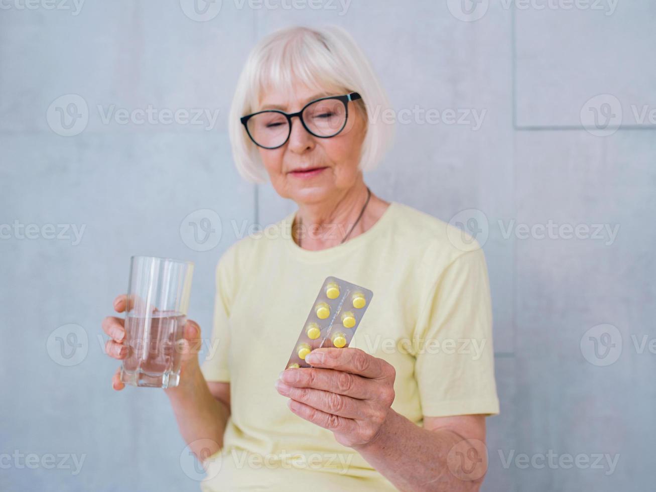 mujer mayor en vasos con medicina y vaso de agua. edad, cuidado de la salud, concepto de tratamiento foto