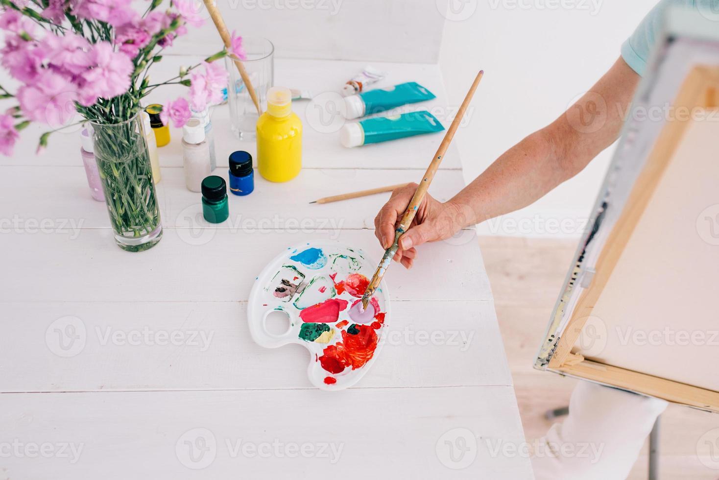 Artista senior mujer alegre en vasos con cabello gris pintando flores en florero. creatividad, arte, pasatiempo, concepto de ocupación foto