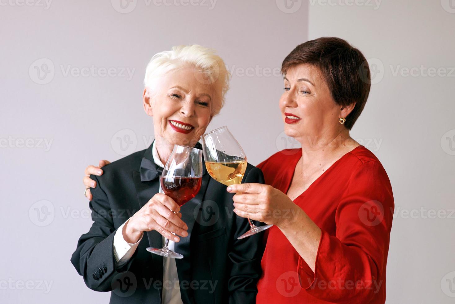 Two beautiful stylish mature senior women drinking wine. Fun, party, style, celebration concept photo