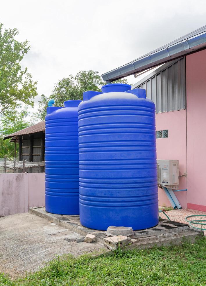 Tanque de agua de plástico azul en el área de la casa. foto