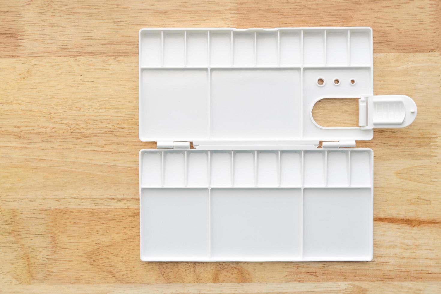 White watercolor palette. Empty watercolor tray isolated on wood background. photo