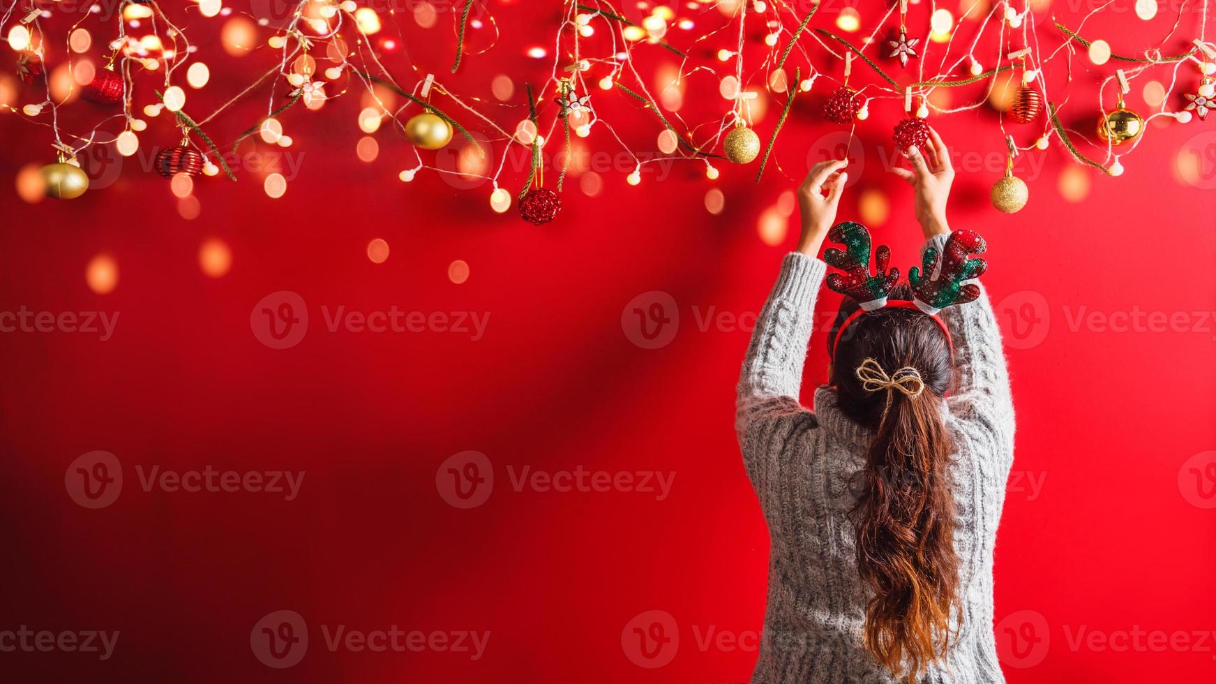 feliz navidad y próspero año nuevo.la niña está diseñando con adornos navideños. el fondo de navidad rojo. con espacio de copia para su texto. Luces led foto