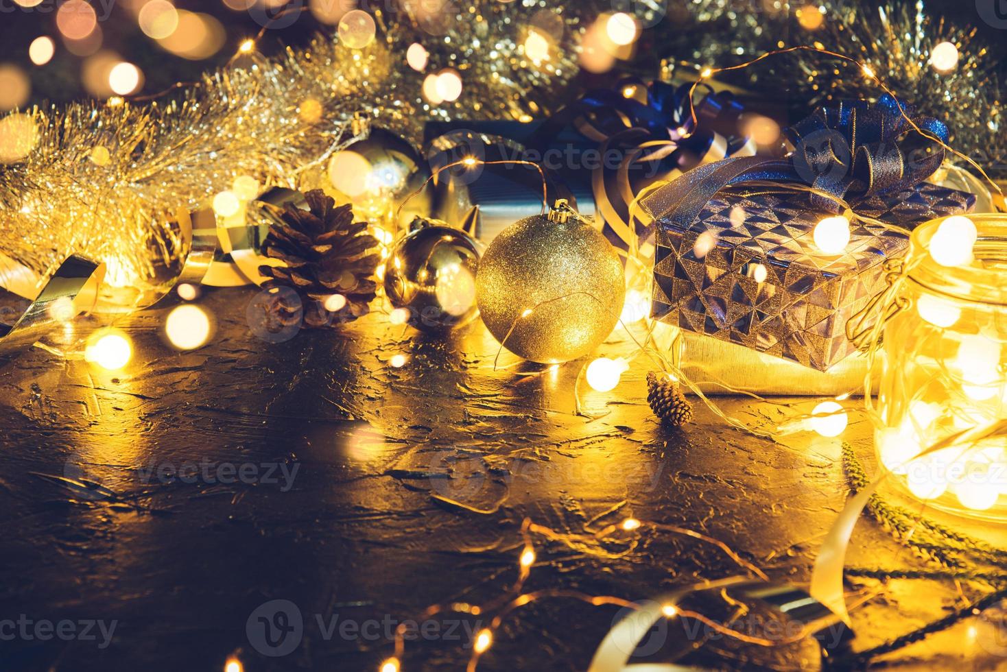 Christmas gift with blue ribbon and Christmas decoration balls on abstract bokeh black background with copy space and decorative LED lights. Merry Christmas and New Year. photo