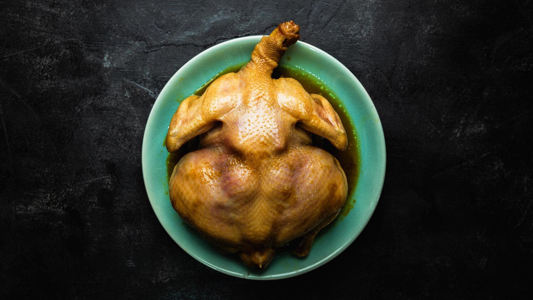 vista desde arriba de pollo entero en la mesa. Pollo entero asado en un plato verde. foto
