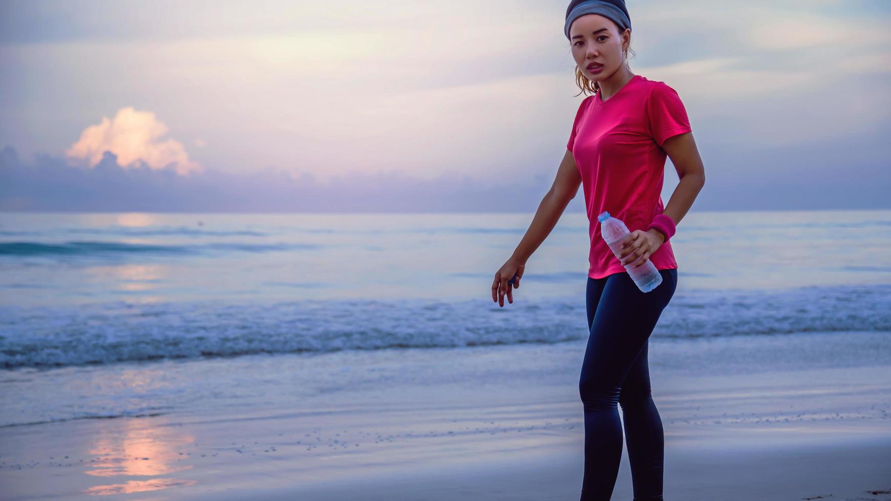 Asian women jogging workout on the beach in the morning. Relax with the sea walk and drinking water from the plastic bottles photo