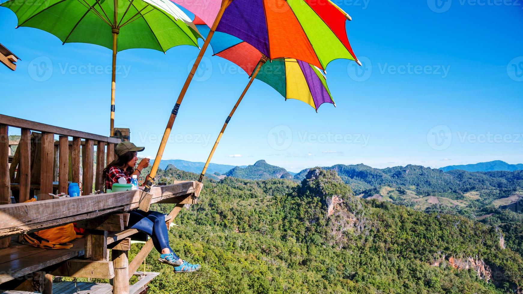 la niña sentada comiendo fideos en el estilo de las piernas colgantes de la aldea rural para el mirador en la montaña, las atracciones locales de la provincia de mae hong son en tailandia. foto