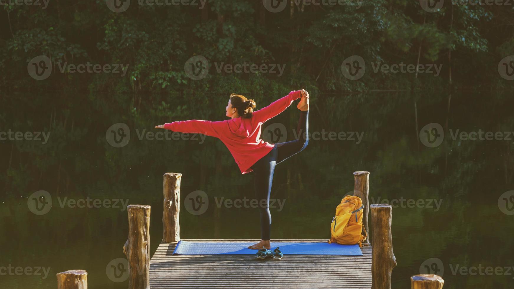 las mujeres asiáticas se relajan en las vacaciones. jugar si yoga. en la montaña, hacer ejercicio, jugar si yoga en el puente de bambú junto al lago en la niebla en pang ung, tailandia. foto