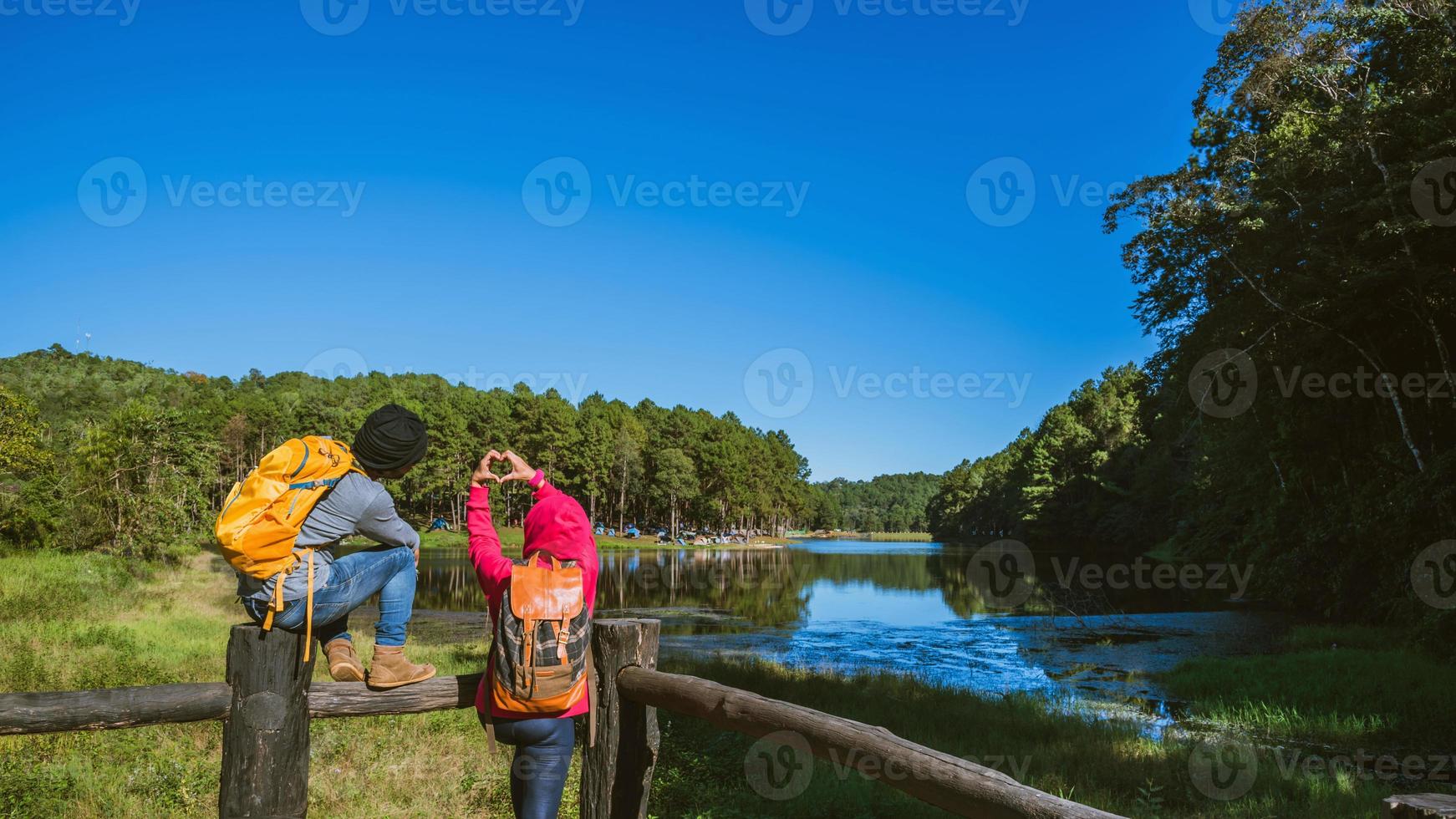 una pareja de viajeros con mochila de pie en la cima del mirador naturaleza hermosa, disfruta del amanecer en la superficie del lago brumoso, hombres jóvenes y novias asiáticas viajan por la naturaleza en la montaña foto