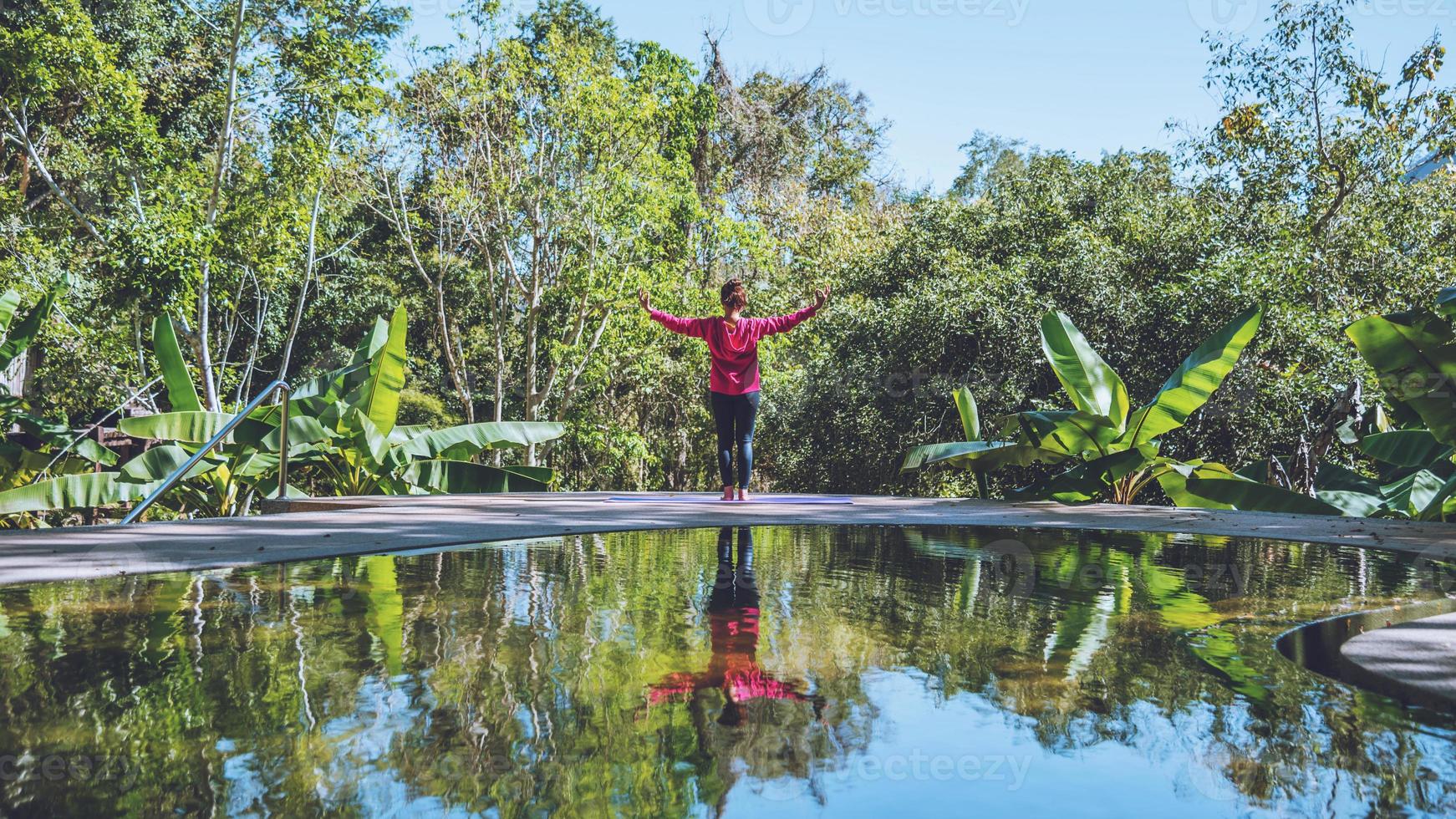 Young woman travel nature she standing exercise at the pool relaxing, Reflections of Asian woman on the water surface. photo