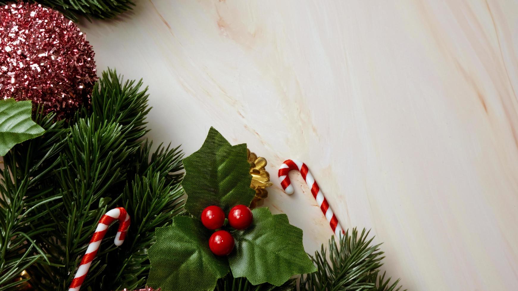 Green pine tree leaves, pink christmas decorations and candy canes on soft marble background, christmas decorations in bright and fancy pink color. Simple and creative christmas concept. photo