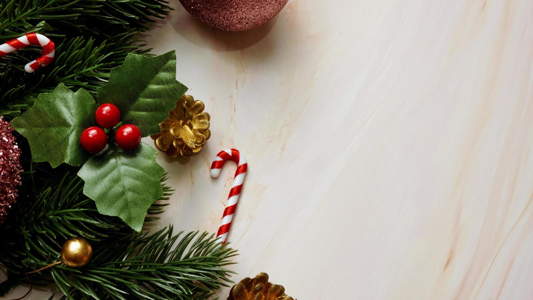 Green pine tree leaves, pink christmas decorations and candy canes on soft marble background, christmas decorations in bright and fancy pink color. Simple and creative christmas concept. photo