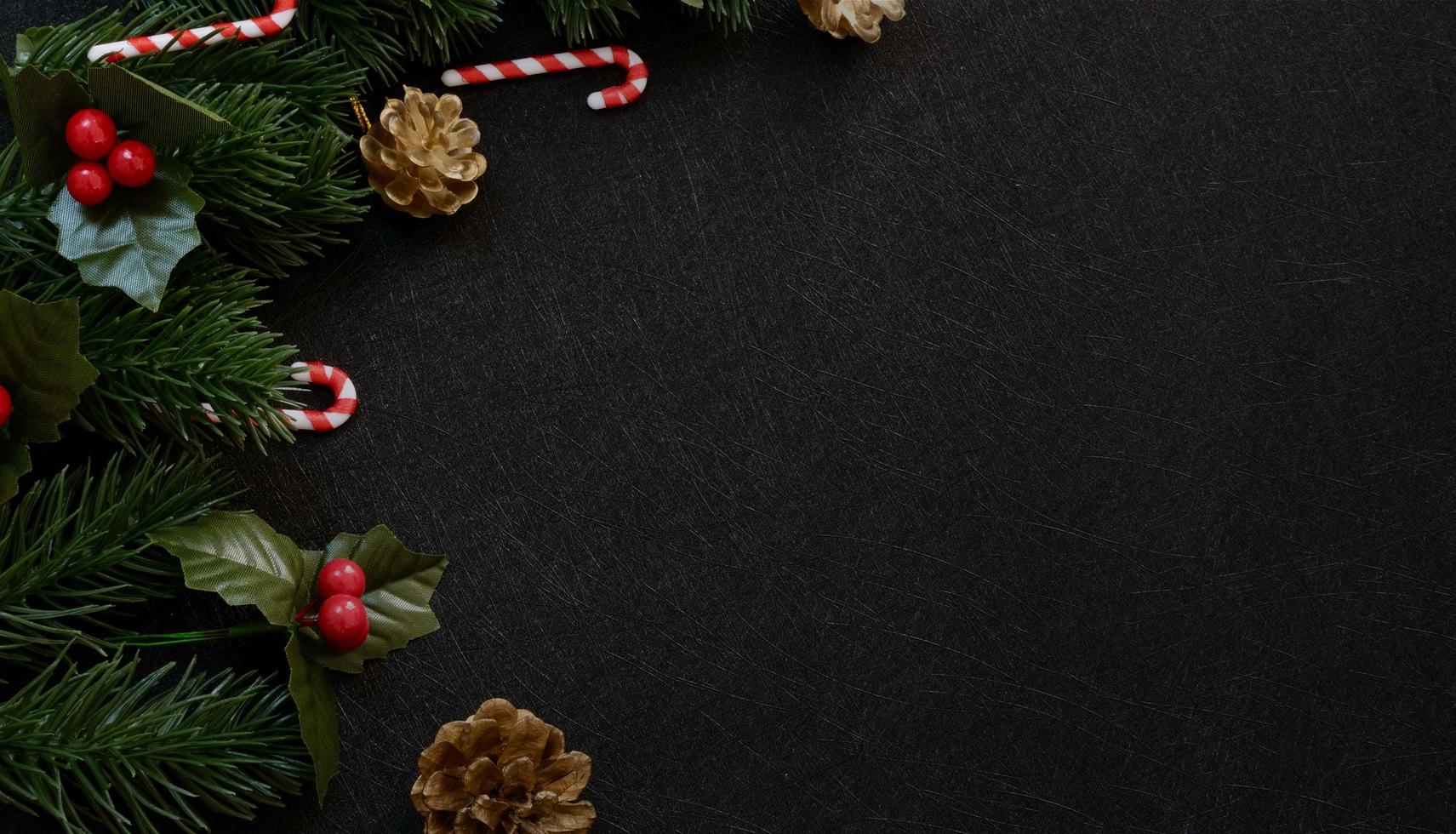 Top view christmas decorations, pine tree fir leaves, candy cane and red berries on dark black textured background photo